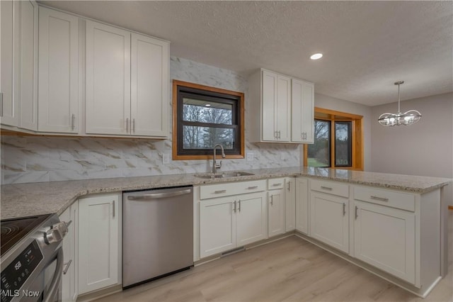 kitchen featuring sink, appliances with stainless steel finishes, a notable chandelier, light hardwood / wood-style floors, and white cabinetry