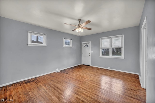 spare room with a wealth of natural light, ceiling fan, and wood-type flooring