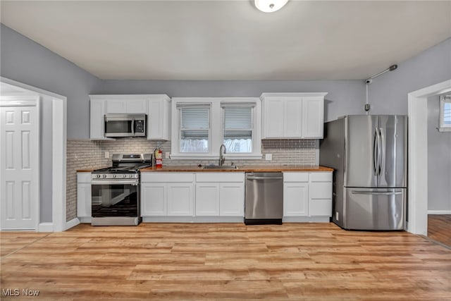 kitchen with white cabinetry, sink, stainless steel appliances, and light wood-type flooring