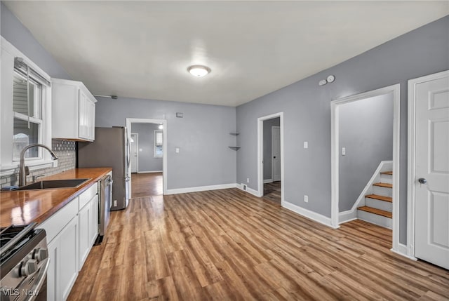 kitchen featuring white cabinets, light hardwood / wood-style floors, butcher block counters, and stainless steel appliances