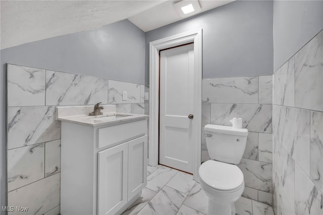 bathroom with vanity, a textured ceiling, toilet, and tile walls