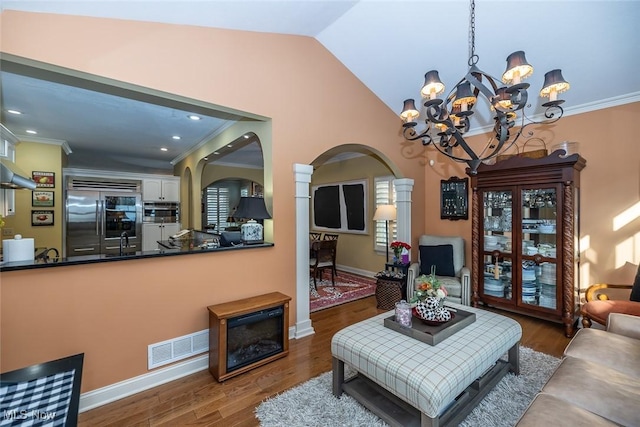 living room with ornamental molding, dark wood-type flooring, sink, an inviting chandelier, and lofted ceiling