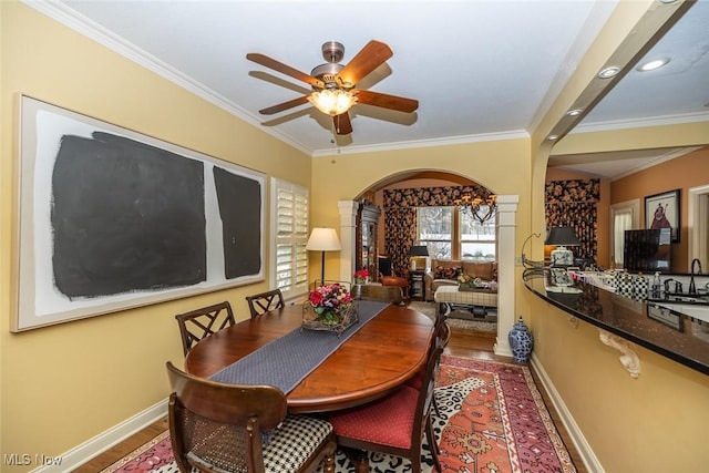 dining room featuring hardwood / wood-style flooring, ceiling fan, sink, and crown molding