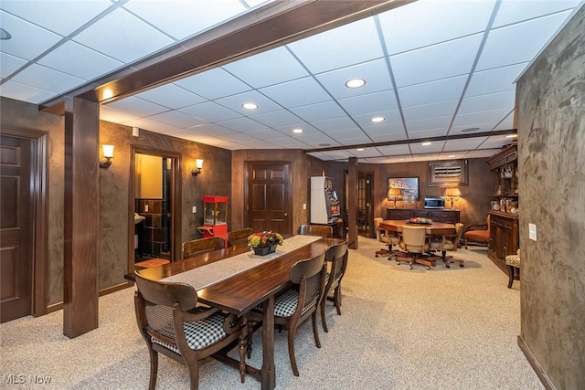 carpeted dining area with a drop ceiling and wood walls