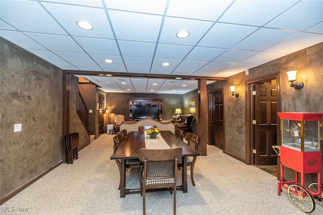 carpeted dining space with a paneled ceiling