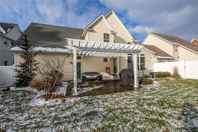 snow covered rear of property featuring a pergola and a lawn