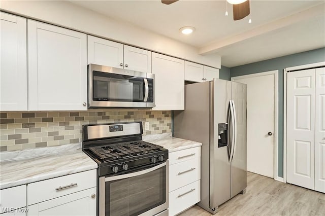 kitchen with backsplash, white cabinets, light stone countertops, light hardwood / wood-style floors, and stainless steel appliances