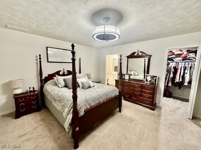 carpeted bedroom with a walk in closet, a textured ceiling, and a closet