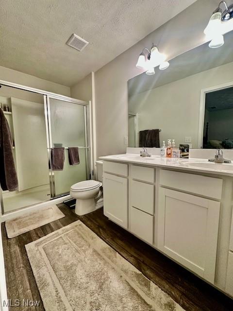 bathroom featuring vanity, a textured ceiling, a shower with door, wood-type flooring, and an inviting chandelier