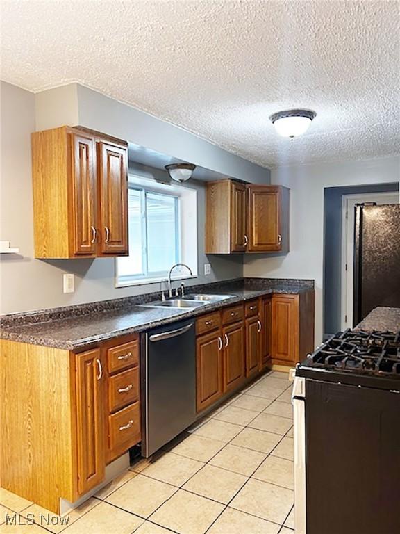 kitchen featuring gas range, refrigerator, a textured ceiling, and stainless steel dishwasher