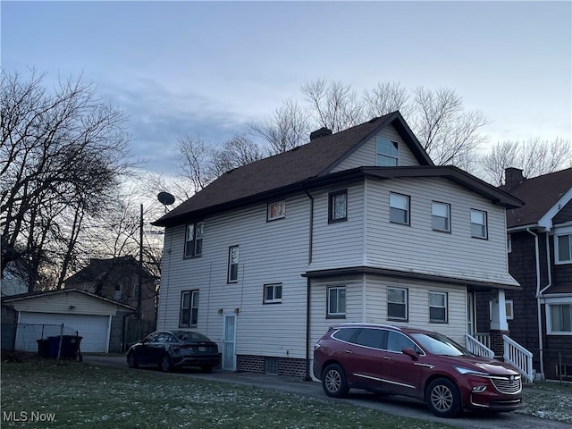 view of property exterior featuring a garage, an outbuilding, and a chimney