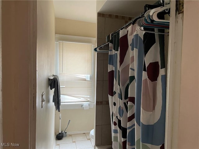 bathroom featuring toilet, a shower with shower curtain, and tile patterned floors