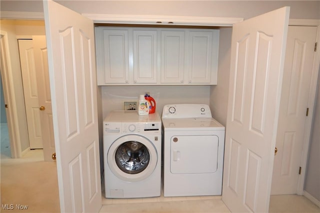 clothes washing area featuring washer and dryer and cabinets