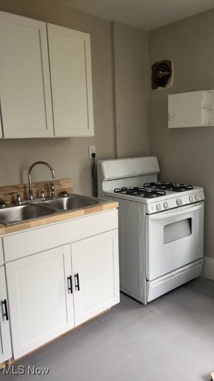 kitchen with white cabinets, white gas range, and sink