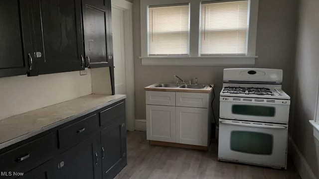 kitchen featuring white gas range, sink, white cabinets, and light hardwood / wood-style flooring