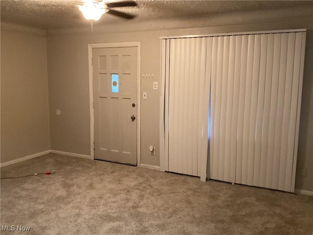 entryway with carpet flooring, ceiling fan, and a textured ceiling