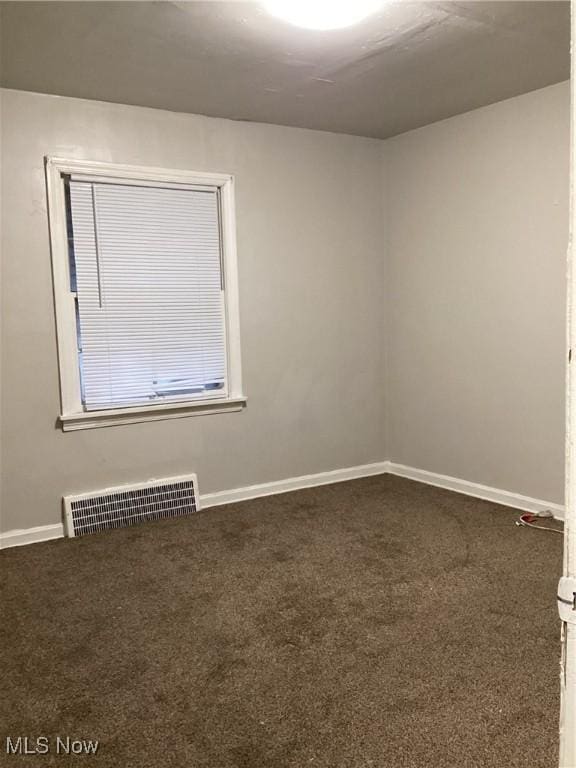 spare room with dark colored carpet