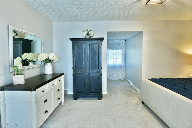 bedroom featuring light colored carpet and a textured ceiling