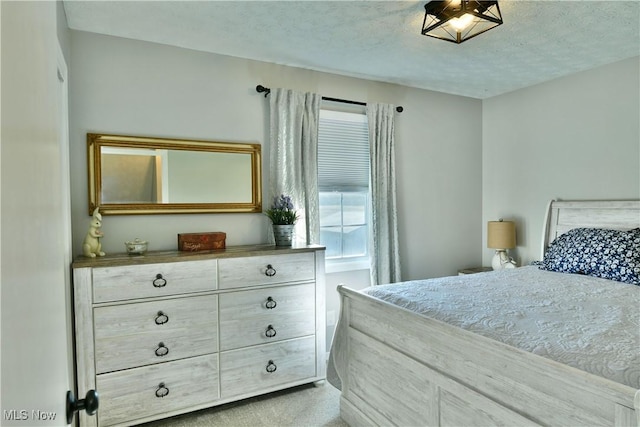 bedroom featuring a textured ceiling and light colored carpet