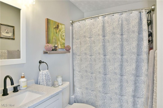 bathroom featuring curtained shower, vanity, a textured ceiling, and toilet