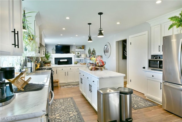 kitchen featuring a kitchen island, white cabinets, hanging light fixtures, and appliances with stainless steel finishes