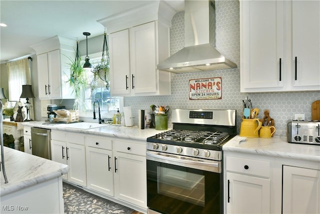 kitchen with white cabinets, appliances with stainless steel finishes, decorative backsplash, and wall chimney range hood