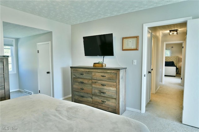 bedroom with light colored carpet and a textured ceiling