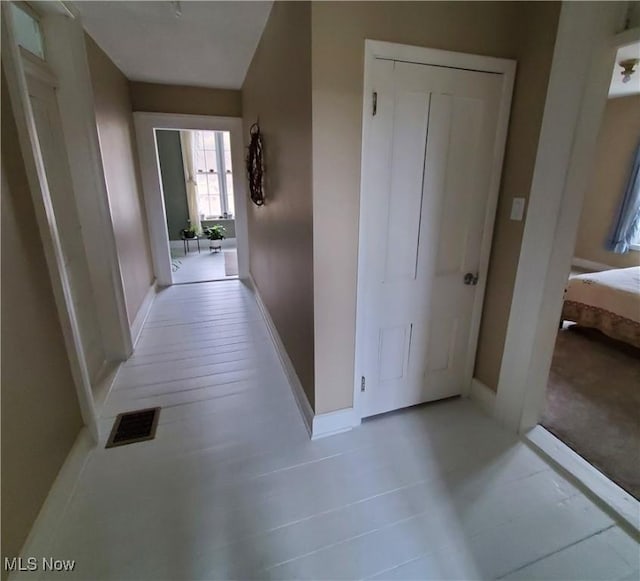 corridor with baseboards and visible vents