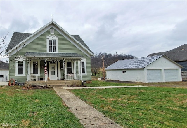 view of front of property featuring a garage, covered porch, an outbuilding, and a front yard