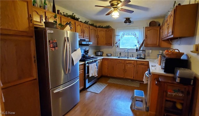 kitchen with ceiling fan, sink, ventilation hood, light hardwood / wood-style flooring, and stainless steel appliances