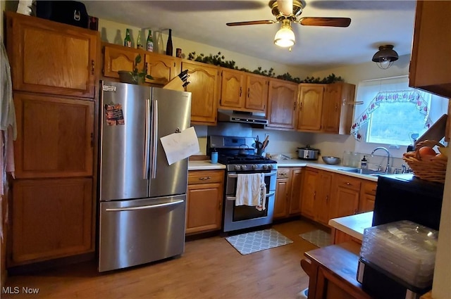 kitchen with ceiling fan, appliances with stainless steel finishes, a sink, light countertops, and under cabinet range hood