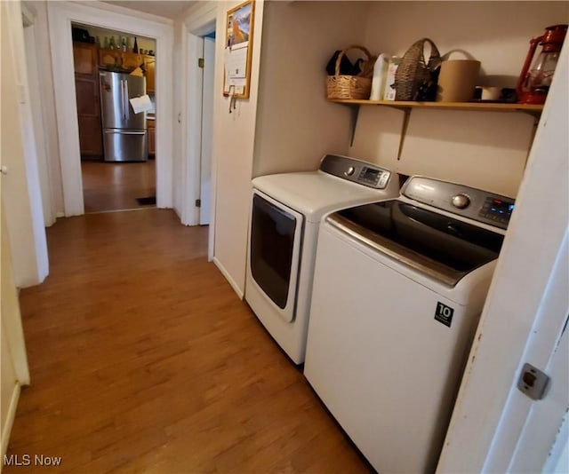 laundry area featuring light hardwood / wood-style flooring and washing machine and clothes dryer