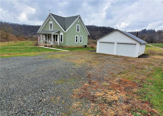 view of front of home with a porch, a garage, and an outbuilding