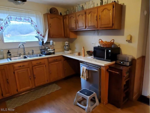 kitchen featuring wood finished floors, black microwave, light countertops, brown cabinets, and a sink