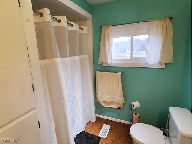 bathroom featuring toilet, hardwood / wood-style floors, and a shower with curtain