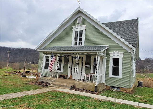 view of front facade with roof with shingles, a porch, central AC, and a front yard