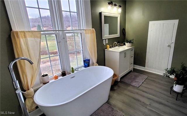 full bathroom with a soaking tub, baseboards, wood finished floors, and vanity