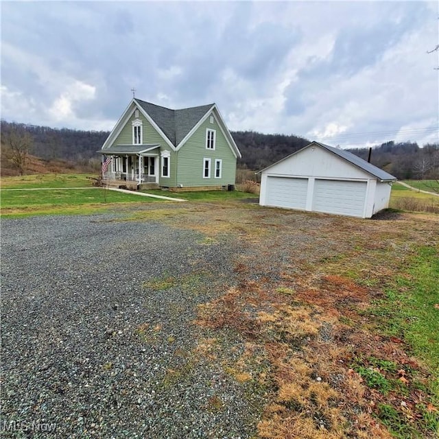 view of front of home featuring a porch, a garage, and an outbuilding