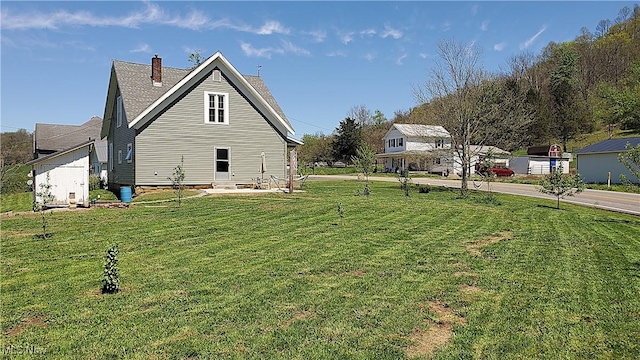 view of side of property featuring a lawn and a chimney