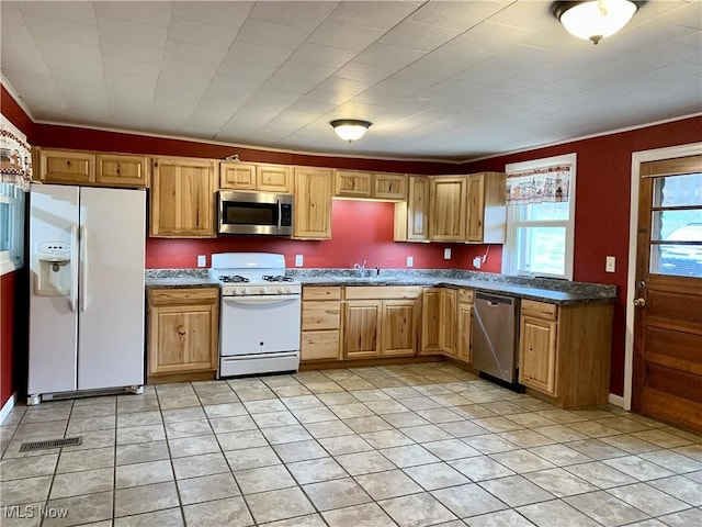 kitchen with light tile patterned floors, sink, appliances with stainless steel finishes, and ornamental molding