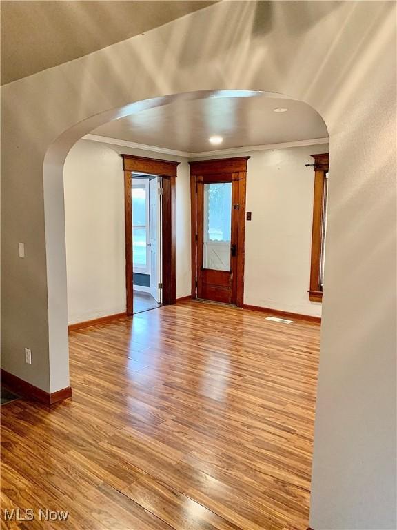 unfurnished room with ornamental molding and light wood-type flooring