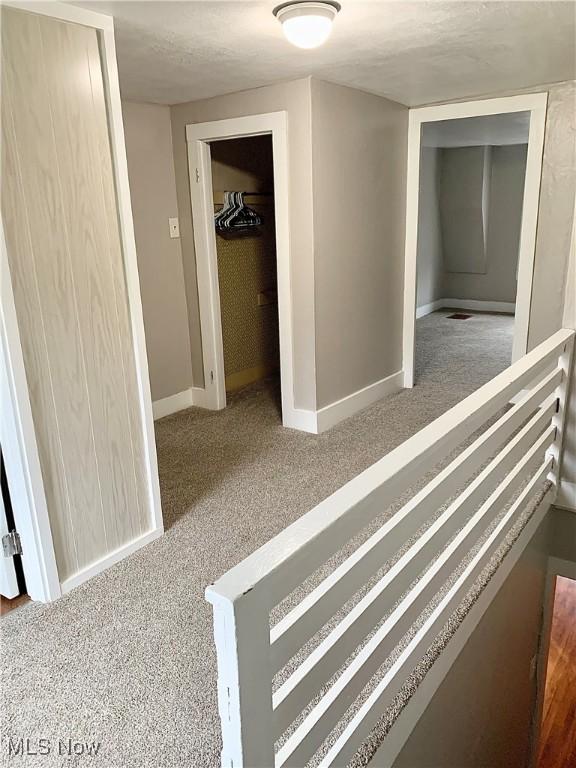 hall featuring dark colored carpet