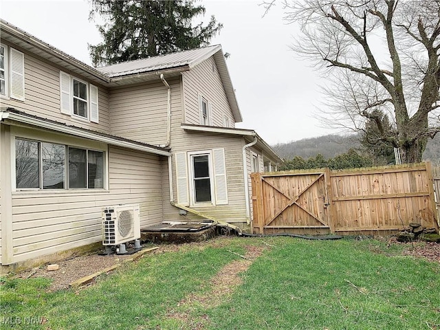 rear view of property with a lawn and ac unit