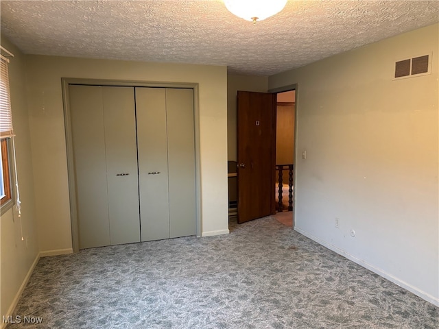 unfurnished bedroom with a textured ceiling, carpet floors, and a closet