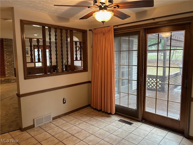 entryway featuring ceiling fan, light tile patterned flooring, and a textured ceiling