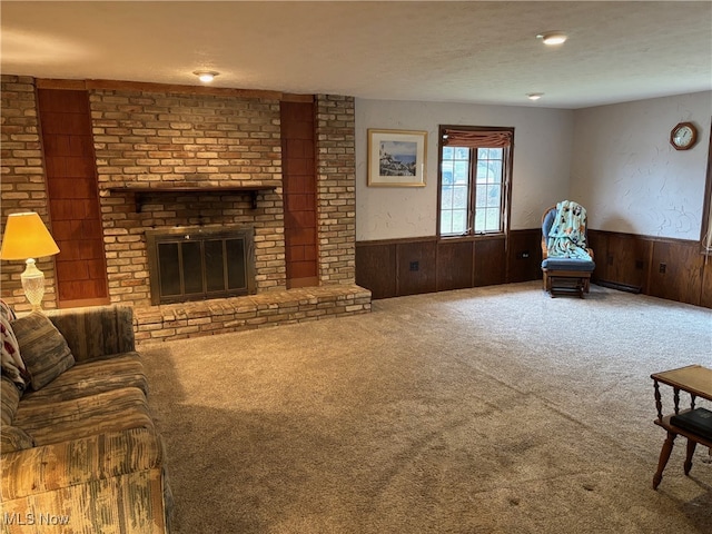 living room with carpet, a textured ceiling, a brick fireplace, and wooden walls