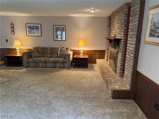 living room featuring wooden walls, carpet, a textured ceiling, and a brick fireplace