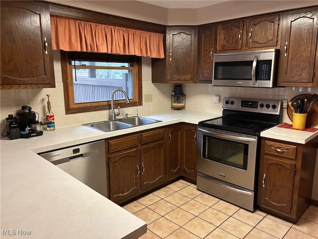 kitchen featuring light tile patterned flooring, appliances with stainless steel finishes, tasteful backsplash, and sink