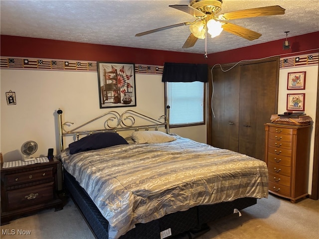 bedroom with a textured ceiling, ceiling fan, light carpet, and a closet