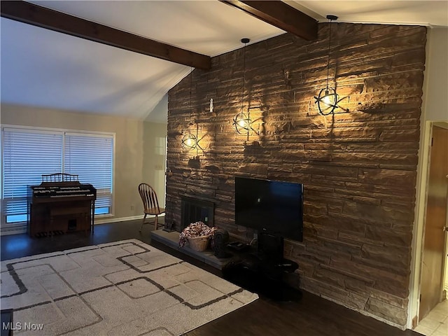 living room with lofted ceiling with beams, hardwood / wood-style flooring, and a stone fireplace